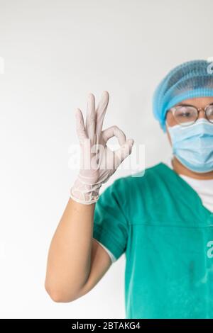 Covid-19, Coronavirus, Medizin, Gesundheit und Menschen Konzept - glücklich männlichen Arzt mit medizinischer Maske im Krankenhaus zeigt ok Handzeichen, Sicherheitsschild. Stockfoto