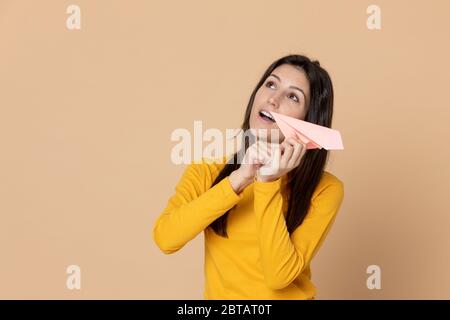 Brünette junge Frau trägt ein gelbes T-Shirt auf einem gelben Hintergrund Stockfoto