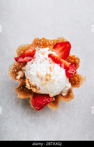 Vanilla Ice Cream holt sich Erdbeerstücke in den Waffelkorb, ein einfaches Dessert zu Hause Stockfoto
