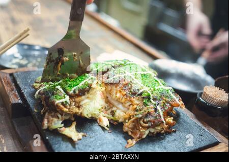 In Osaka, japanisches Soul Food aus der Region Kansai, ist das Okonomiyaki eine Pizza oder ein Pfannkuchen-Gericht, das mit Kohl, Algen, Mayonnaise und Reismochi gegrillt wird Stockfoto