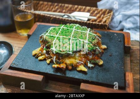 In Osaka, japanisches Soul Food aus der Region Kansai, ist das Okonomiyaki eine Pizza oder ein Pfannkuchen-Gericht, das mit Kohl, Algen, Mayonnaise und Reismochi gegrillt wird Stockfoto
