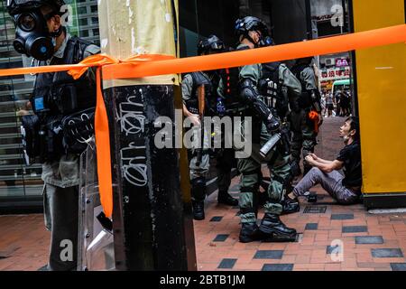Polizeibeamte der Bereitschaftspolizei verhören während der Demonstration einen Protestierenden.im Lichte eines neuen nationalen Sicherheitsgesetzes, das die Autonomie Hongkongs bedrohen würde, marschierten Demonstranten und blockierten Straßen. Später tauchte die Polizei in Bereitschaftspolizei auf und feuerte Tränengas und Pfefferspray ab, um mehrere Demonstranten zu verhaften. Stockfoto