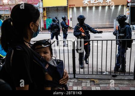 Eine Mutter und ihr Kind schauten während der Demonstration Polizisten mit Gewehren an.im Lichte eines neuen nationalen Sicherheitsgesetzes, das die Autonomie Hongkongs bedrohen würde, marschierten Demonstranten und blockierten Straßen. Später tauchte die Polizei in Bereitschaftspolizei auf und feuerte Tränengas und Pfefferspray ab, um mehrere Demonstranten zu verhaften. Stockfoto