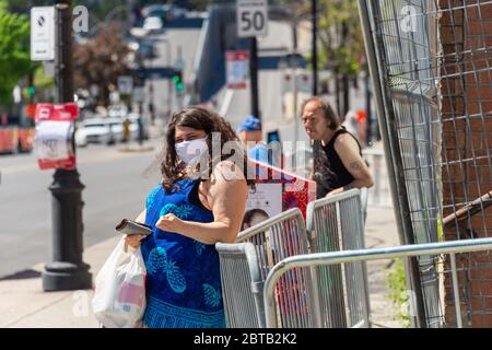Montreal, CA - 23. Mai 2020: Frau mit Gesichtsmaske zum Schutz vor COVID-19 wartet auf den Bus Stockfoto