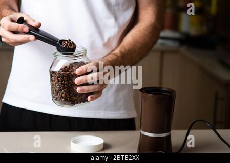 Mann, der Kaffeebohnen für die Zubereitung eines Espresso mahlen kann. Lifestyle-Konzept für den Barista im Haus Stockfoto