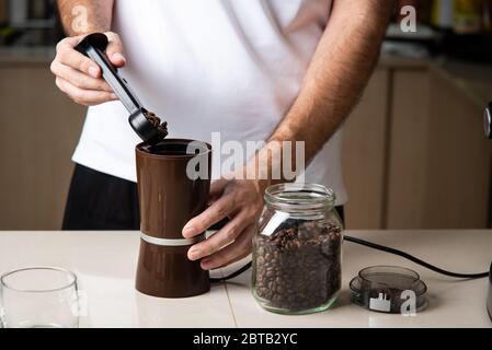 Mann, der Kaffeebohnen für die Zubereitung eines Espresso mahlen kann. Lifestyle-Konzept für den Barista im Haus Stockfoto