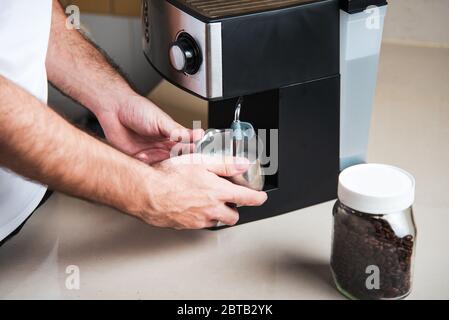 Person, die Milchaufschäumer für die Espressomaschine zum Kaffeekochen verwendet. Lifestyle-Konzept für den Barista im Haus Stockfoto