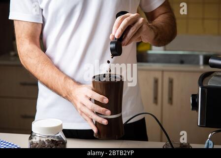 Mann, der Kaffeebohnen für die Zubereitung eines Espresso mahlen kann. Lifestyle-Konzept für den Barista im Haus Stockfoto