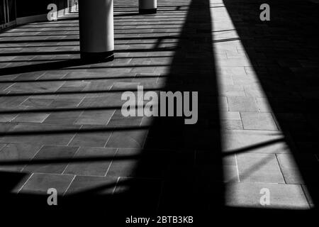 Schwarz-Weiß-Bild von Schatten, die auf eine Fußgängerzone fallen Stockfoto