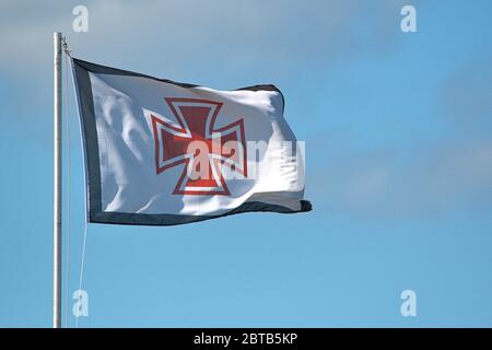 Schleswig, Deutschland. Mai 2020. 19.05.2020, Schleswig, die wehende Flagge der Deutschen Gesellschaft zur Rettung von Schiffswracks (DGzRS) mit Hansekreuz am blauen Himmel im Schleswig-Hafen an der Schlei. Die DGzRS ist die deutsche Nichtregierungsorganisation zur Seenotrettung, die für den Such- und Rettungsdienst (SAR: Such- und Rettungsdienst) im Falle von Seenotfallen in der deutschen Nord- und Ostsee zuständig ist. --- nur für redaktionelle Zwecke! --- nur für redaktionelle Verwendung! Nutzung weltweit Kredit: dpa/Alamy Live News Stockfoto