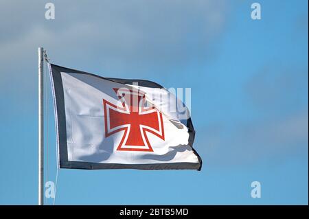 Schleswig, Deutschland. Mai 2020. 19.05.2020, Schleswig, die wehende Flagge der Deutschen Gesellschaft zur Rettung von Schiffswracks (DGzRS) mit Hansekreuz am blauen Himmel im Schleswig-Hafen an der Schlei. Die DGzRS ist die deutsche Nichtregierungsorganisation zur Seenotrettung, die für den Such- und Rettungsdienst (SAR: Such- und Rettungsdienst) im Falle von Seenotfallen in der deutschen Nord- und Ostsee zuständig ist. --- nur für redaktionelle Zwecke! --- nur für redaktionelle Verwendung! Nutzung weltweit Kredit: dpa/Alamy Live News Stockfoto