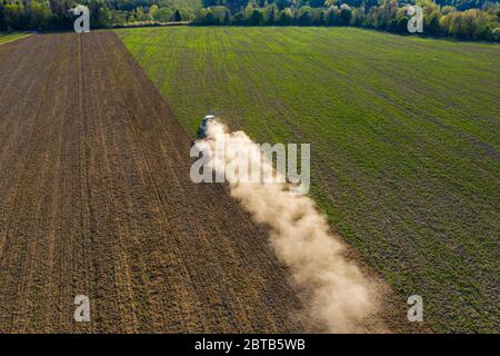 Ein Raupentraktor kultiviert den Boden in einem landwirtschaftlichen Feld. Draufsicht Fliegen auf einer Drohne. Verfolgung im Kreis 2021. Stockfoto