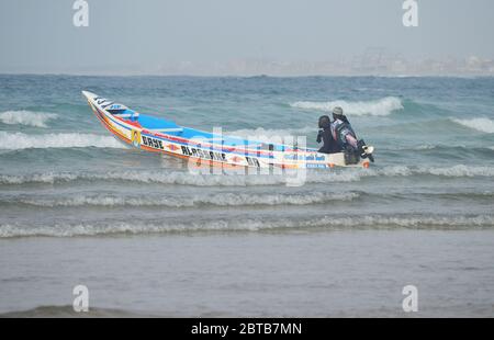 Ein Pirogue (handwerkliches Fischerboot), das sich am Yoff Beach, Dakar, Senegal, der Brandung trotzt Stockfoto