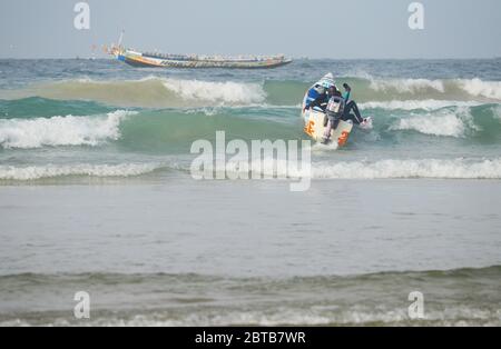 Ein Pirogue (handwerkliches Fischerboot), das sich am Yoff Beach, Dakar, Senegal, der Brandung trotzt Stockfoto