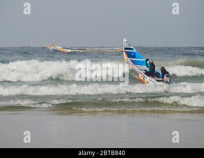 Ein Pirogue (handwerkliches Fischerboot), das sich am Yoff Beach, Dakar, Senegal, der Brandung trotzt Stockfoto