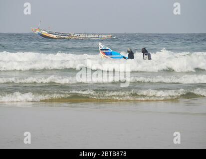 Ein Pirogue (handwerkliches Fischerboot), das sich am Yoff Beach, Dakar, Senegal, der Brandung trotzt Stockfoto