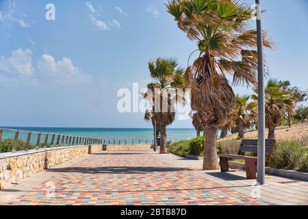 Pilar de la Horadada leere gepflasterte Promenade in der Nähe des Mittelmeers bei windigem Wetter, keine Menschen sonnig warmen Tag. Tourismus und Urlaub, Sommerurlaub Stockfoto