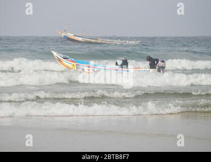 Ein Pirogue (handwerkliches Fischerboot), das sich am Yoff Beach, Dakar, Senegal, der Brandung trotzt Stockfoto