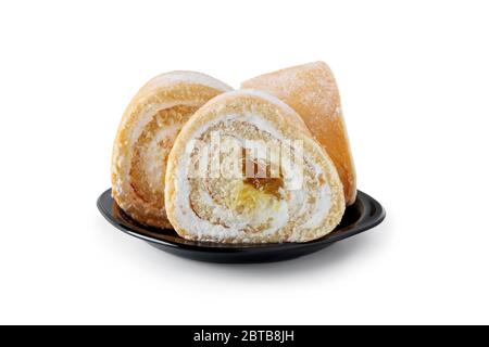 Süße Rolle mit zarter Buttercreme und Fruchtfüllung auf einer Porzellanuntertasse auf weiß isoliert Stockfoto
