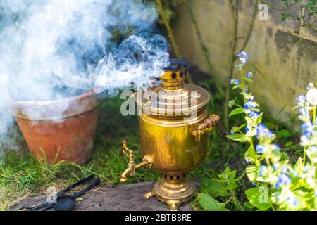 Alte Vintage Samowar mit Rauch. Tee auf altmodische Weise brauen. Russische Zeremonie Stockfoto