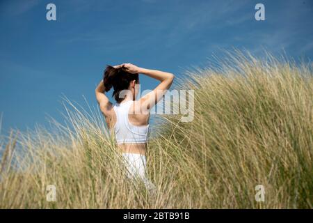Sportliche Frau, die beim Training im Freien ihr Haar festschnürt Stockfoto