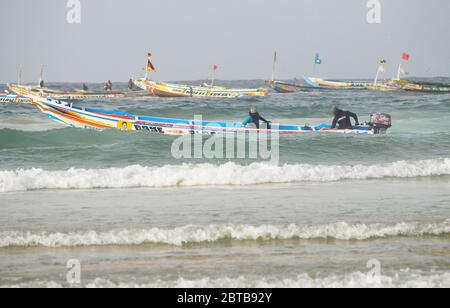 Ein Pirogue (handwerkliches Fischerboot), das sich am Yoff Beach, Dakar, Senegal, der Brandung trotzt Stockfoto