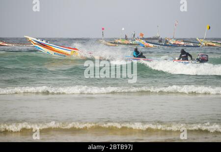 Ein Pirogue (handwerkliches Fischerboot), das sich am Yoff Beach, Dakar, Senegal, der Brandung trotzt Stockfoto