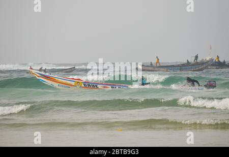 Ein Pirogue (handwerkliches Fischerboot), das sich am Yoff Beach, Dakar, Senegal, der Brandung trotzt Stockfoto