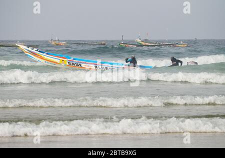 Ein Pirogue (handwerkliches Fischerboot), das sich am Yoff Beach, Dakar, Senegal, der Brandung trotzt Stockfoto