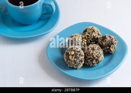 Eine Tasse schwarzen Kaffee und Energiebälle auf einem weißen Tisch. Gesundes Frühstück wird Sie mit Energie füllen Stockfoto