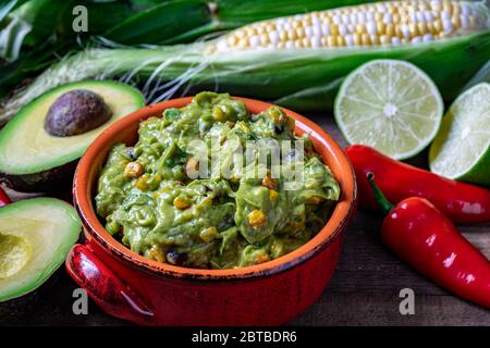 Guacamole Sauce mit geröstetem Mais und Rohzutaten Stockfoto