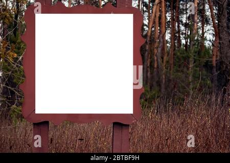 Weißes Quadrat in einem braunen Holzrahmen auf einem Waldhintergrund. Platz für Text, Banner, Mockup Stockfoto