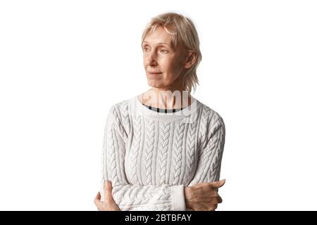 Freistil. Ältere Frau in Pullover stehend isoliert auf weißen gekreuzten Armen Blick neben verträumt Stockfoto