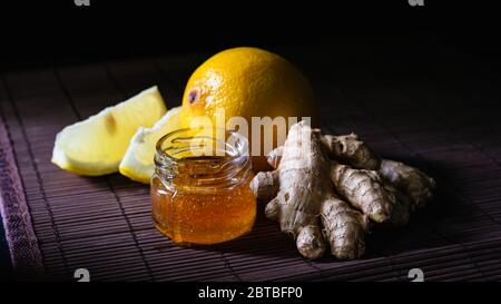 Stillleben Ingwer, Zitrone und ein Glas Honig auf dunklem Hintergrund Stockfoto