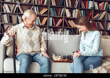 Vater und Tochter zu Hause Bibliothek sitzen Schach spielen freudig Stockfoto