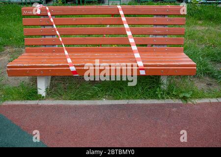 Rote und weiße Linien von Absperrband auf einer Bank. Warnband. Das Verbot, im Park zu gehen. Quarantäne. Platz für Text kopieren Stockfoto