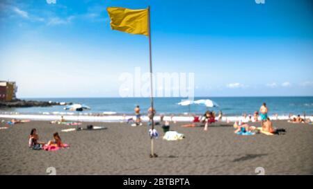 Verschwommen unscharf iamg eof gelbe Flagge am Meeresstrand und sonnigen windigen Tag Stockfoto