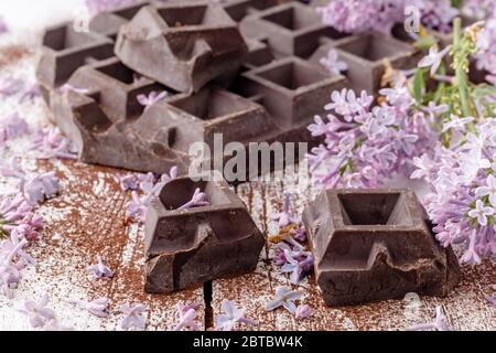 Dunkle Schokolade auf dem Tisch mit Liliablüten Stockfoto