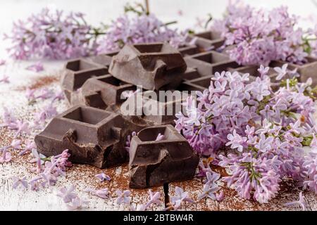 Dunkle Schokolade auf dem Tisch mit Liliablüten Stockfoto