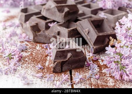 Dunkle Schokolade auf dem Tisch mit Liliablüten Stockfoto