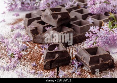 Dunkle Schokolade auf dem Tisch mit Liliablüten Stockfoto