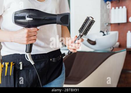 Haartrockner, Kamm Bürste in Friseuren Hände gegen Schönheitssalon, Friseur-Shop Interieur, Waschbecken Chaire. Professionelle Werkzeuge für einen Friseur, Haar Stockfoto