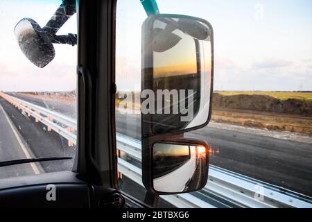 Im Cockpit eines LKWs bei Sonnenaufgang. Große Rückspiegel Stockfoto