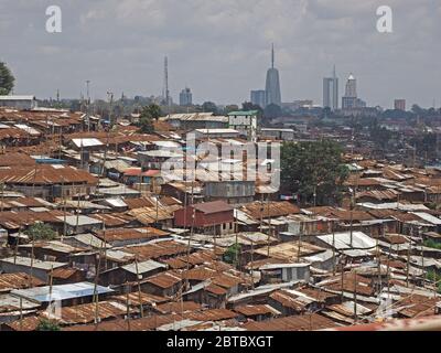Blick über die Blechdächer des berüchtigten Kibera Slum Distrikts auf eine Skyline moderner Wolkenkratzer-Gebäude des 21. Jahrhunderts Nairobi in Kenia, Afrika Stockfoto