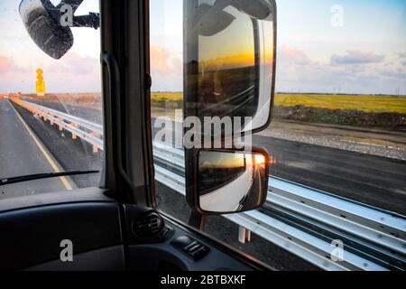 Im Cockpit eines LKWs bei Sonnenaufgang. Große Rückspiegel Stockfoto