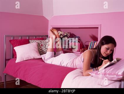 Teenager-Mädchen, das auf dem Bett liegt und Tagebuch schreibt NUR REDAKTIONELLE VERWENDUNG Stockfoto