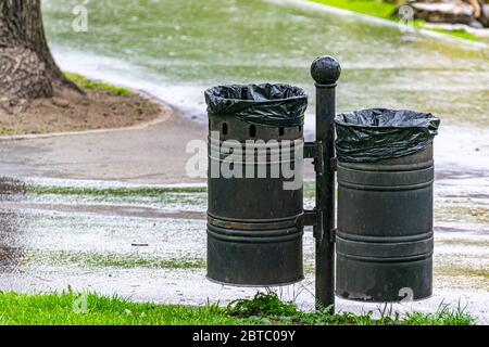Mülltonne im öffentlichen Park. Mülltonnen in einem Stadtpark entlang Fußgänger- und Fahrradwegen. Stockfoto