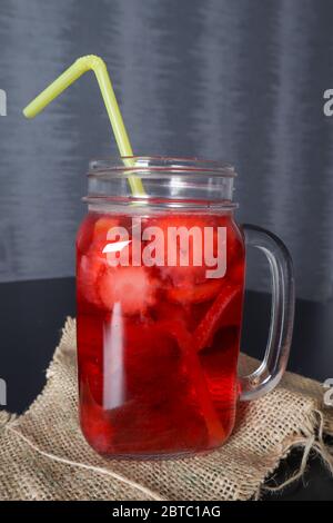 Erdbeer-Smoothie-Drink in einem Glas mit einem Trinkschlauch auf einem Schreibtisch zu Hause dekoriert. Sommer und Saison Essen und Trinken Konzept Stockfoto