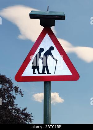Ältere Menschen überqueren Schild auf blauen Himmel mit weißen Wolken Stockfoto