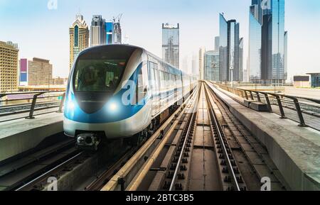 Dubai Metro Zug auf Schienen im Hintergrund von Wolkenkratzern. Berühmte U-Bahn-Linie im Freien. Stockfoto